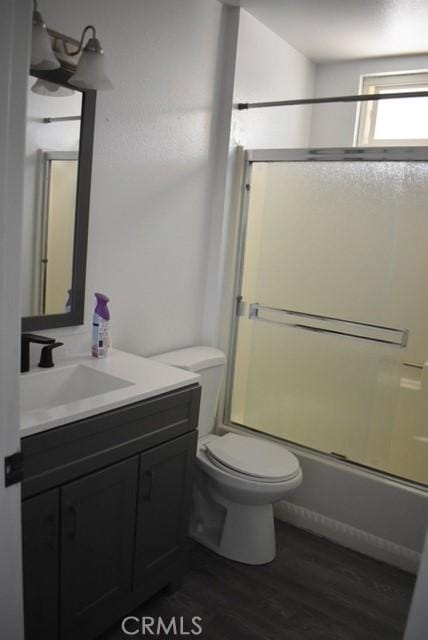 815 California Ave, Dos Palos, CA 93620 - full bathroom featuring vanity, toilet, wood finished floors, and combined bath / shower with glass door