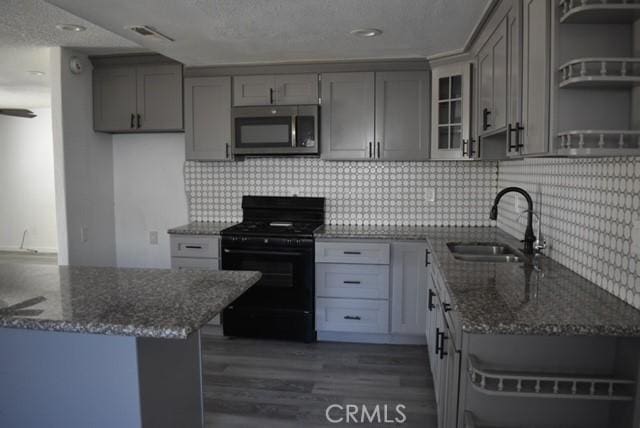 815 California Ave, Dos Palos, CA 93620 - kitchen featuring stainless steel microwave, black gas stove, open shelves, gray cabinetry, and recessed lighting
