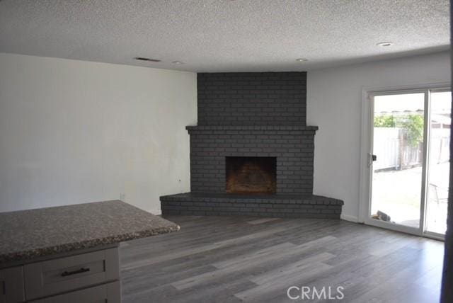 815 California Ave, Dos Palos, CA 93620 - unfurnished living room with a textured ceiling, wood finished floors, and a fireplace
