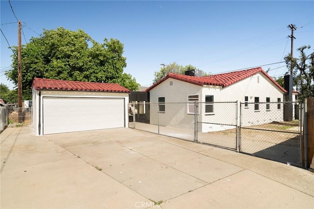 709 E 9th St, Pomona, CA 91766 - mediterranean / spanish-style house with a tile roof, a gate, a garage, stucco siding, and an outbuilding