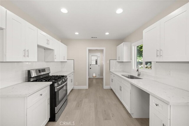 709 E 9th St, Pomona, CA 91766 - kitchen featuring gas range, a sink, light wood finished floors, baseboards, and tasteful backsplash
