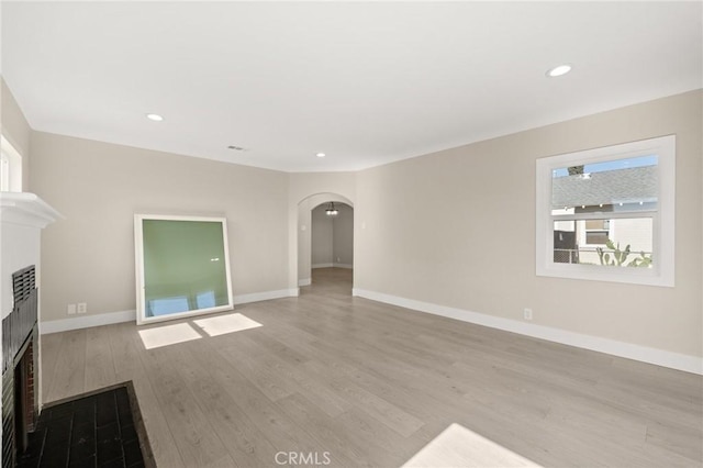 709 E 9th St, Pomona, CA 91766 - unfurnished living room featuring plenty of natural light, arched walkways, a fireplace, light wood-type flooring, and recessed lighting