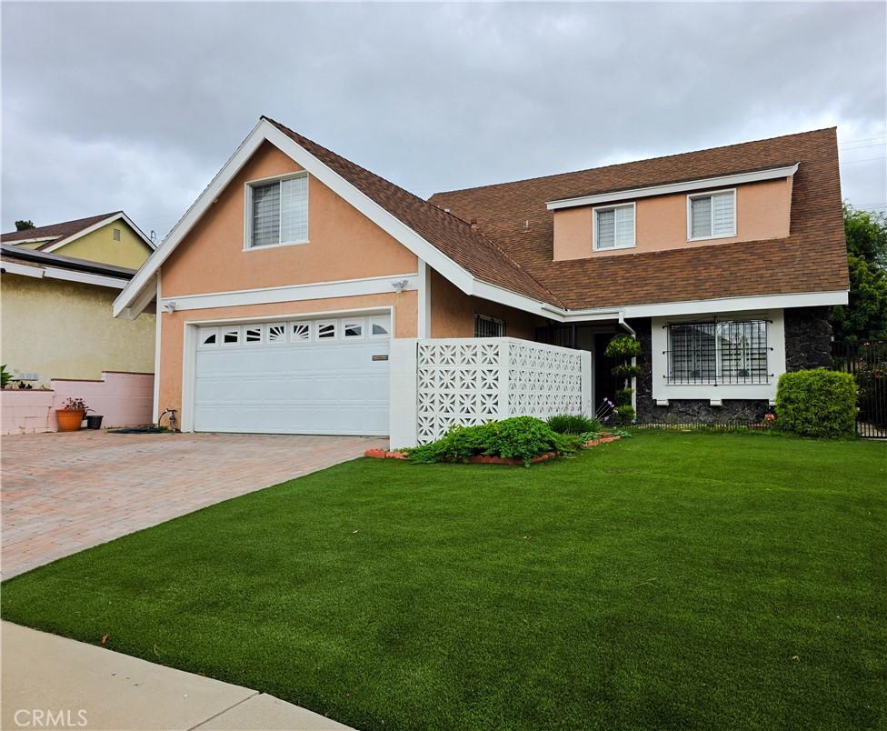 19312 Gunlock, Carson, CA 90746 - traditional home with a front yard, stucco siding, driveway, a shingled roof, and stone siding