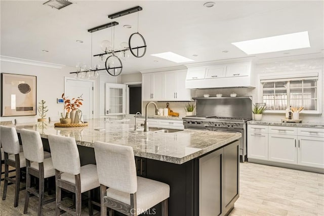 20402 Seven Seas Ln, Huntington Beach, CA 92646 - kitchen featuring a skylight, a spacious island, white cabinetry, ornamental molding, and recessed lighting