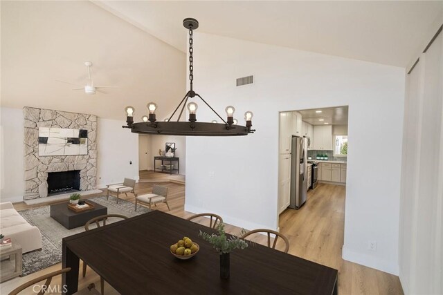 40033 Sagewood Dr, Palm Desert, CA 92260 - dining room with ceiling fan, light wood-style flooring, high vaulted ceiling, and a stone fireplace