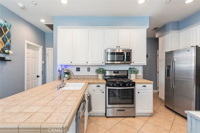 29290 Morena Villa Dr, Highland, CA 92346 - kitchen featuring stainless steel appliances, a sink, tile countertops, a peninsula, and white cabinetry