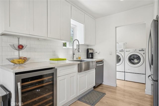 1120 9th St, Hermosa Beach, CA 90254 - kitchen featuring independent washer and dryer, beverage cooler, appliances with stainless steel finishes, a sink, and white cabinets
