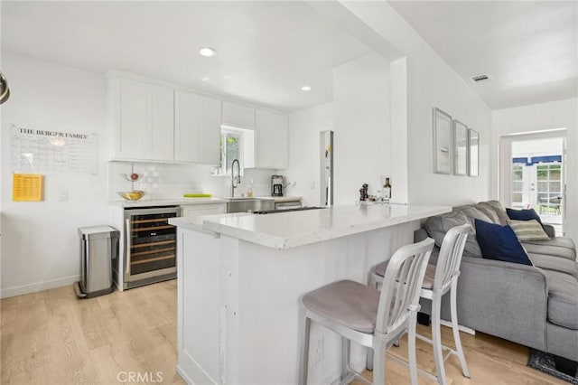 1120 9th St, Hermosa Beach, CA 90254 - kitchen with wine cooler, open floor plan, a breakfast bar, a peninsula, and light wood-style floors