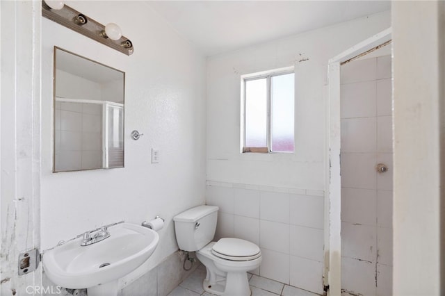 764 N Meridian Ave, Rialto, CA 92376 - bathroom with a sink, toilet, a shower with shower door, tile patterned flooring, and tile walls