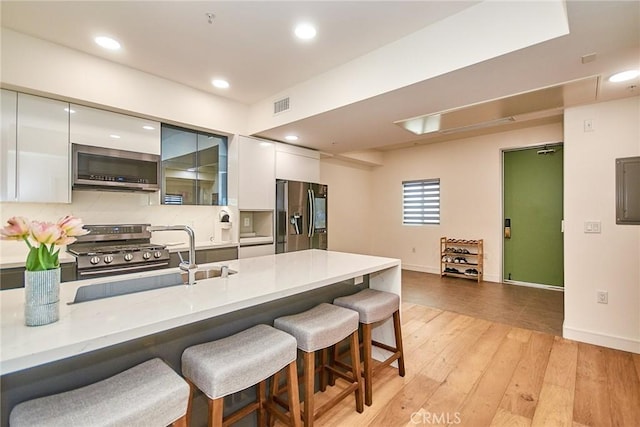 820 S Wilton Pl Unit 304, Los Angeles, CA 90005 - kitchen with stainless steel appliances, modern cabinets, a breakfast bar area, white cabinets, and a sink