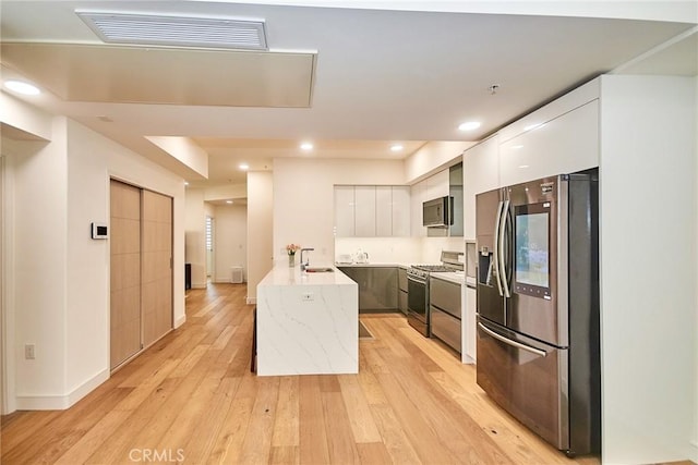 820 S Wilton Pl Unit 304, Los Angeles, CA 90005 - kitchen featuring appliances with stainless steel finishes, modern cabinets, a peninsula, white cabinetry, and light wood-style flooring