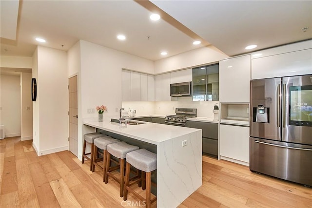 820 S Wilton Pl Unit 304, Los Angeles, CA 90005 - kitchen featuring appliances with stainless steel finishes, a sink, a breakfast bar, modern cabinets, and a peninsula