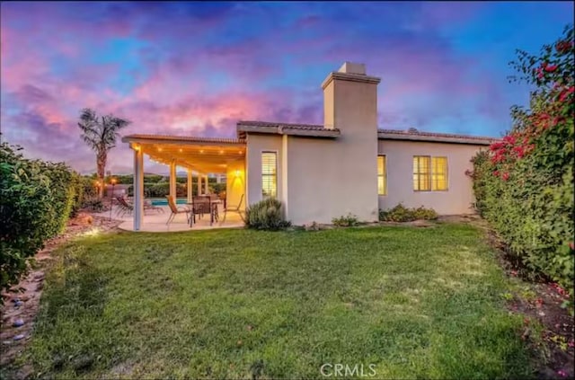 80804 Sunspring Ct, Indio, CA 92201 - back of property featuring a chimney, a patio area, a yard, stucco siding, and a tile roof