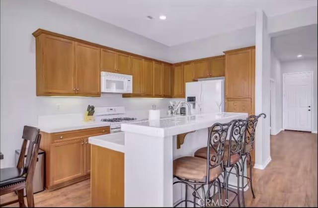 80804 Sunspring Ct, Indio, CA 92201 - kitchen with white appliances, light countertops, a center island with sink, light wood-style floors, and a breakfast bar