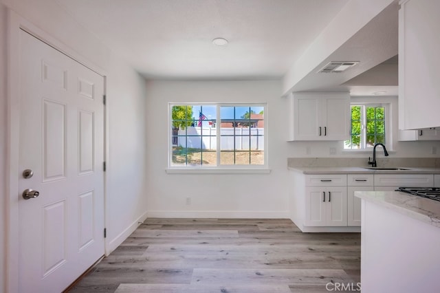 1264 W Etiwanda Ave, Rialto, CA 92376 - kitchen featuring a sink, white cabinetry, light stone countertops, and baseboards