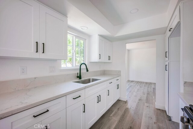 1264 W Etiwanda Ave, Rialto, CA 92376 - kitchen featuring a sink, light wood finished floors, white cabinetry, range, and light stone counters