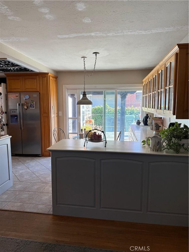 15911 Dundalk Ln, Huntington Beach, CA 92647 - kitchen with stainless steel fridge with ice dispenser, pendant lighting, a textured ceiling, brown cabinets, and a peninsula
