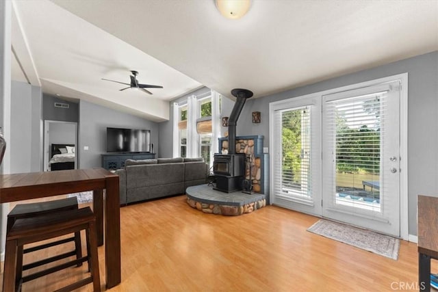 8510 Verdant Ct, Los Molinos, CA 96055 - living room featuring a wood stove, plenty of natural light, ceiling fan, wood finished floors, and vaulted ceiling