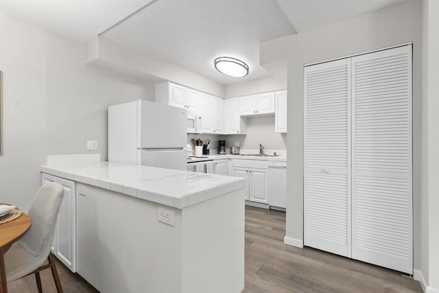 6955 Alvarado Rd Unit 77, San Diego, CA 92120 - kitchen with white appliances, a sink, a peninsula, dark wood-type flooring, and white cabinets