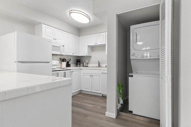 6955 Alvarado Rd Unit 77, San Diego, CA 92120 - kitchen featuring estacked washer and dryer, white appliances, wood finished floors, tile countertops, and white cabinetry