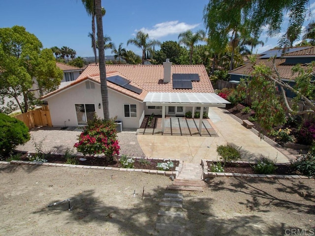 1219 Sunglow Dr, Oceanside, CA 92056 - rear view of property featuring a tile roof, a patio, a chimney, roof mounted solar panels, and stucco siding