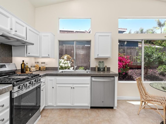 1219 Sunglow Dr, Oceanside, CA 92056 - kitchen with stainless steel appliances, a sink, white cabinetry, dark countertops, and high vaulted ceiling