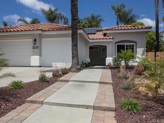 1219 Sunglow Dr, Oceanside, CA 92056 - mediterranean / spanish home featuring stucco siding, a tiled roof, concrete driveway, roof mounted solar panels, and a garage