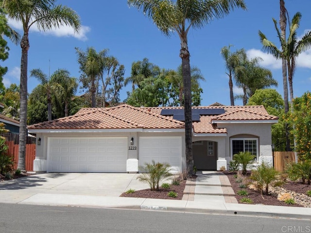 1219 Sunglow Dr, Oceanside, CA 92056 - mediterranean / spanish home with stucco siding, an attached garage, a tiled roof, driveway, and roof mounted solar panels