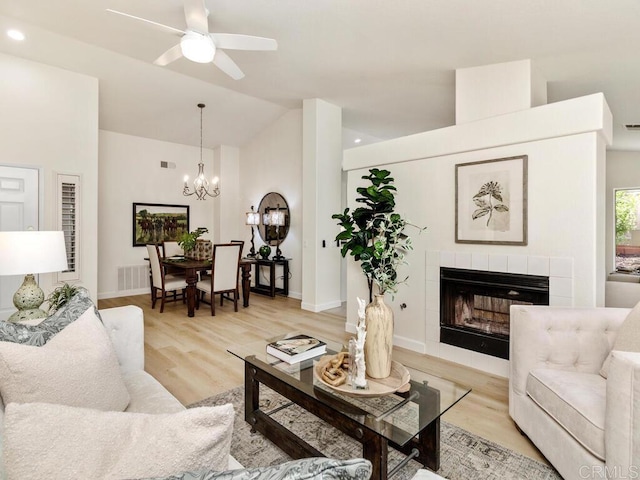 1219 Sunglow Dr, Oceanside, CA 92056 - living room featuring vaulted ceiling, a ceiling fan, a fireplace, a chandelier, and light wood-style floors