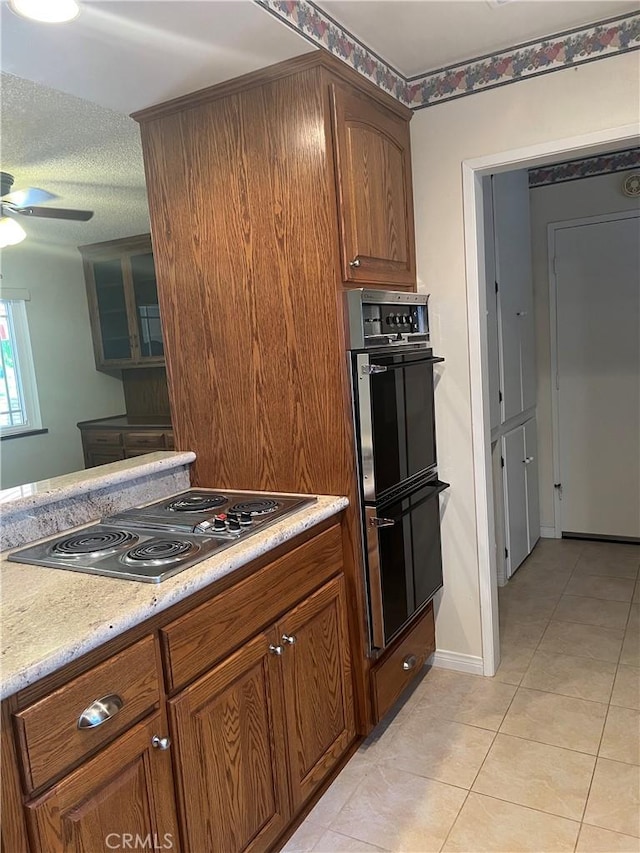 2306 S Rene Dr, Santa Ana, CA 92704 - kitchen featuring a ceiling fan, stainless steel electric cooktop, light tile patterned flooring, light countertops, and brown cabinetry