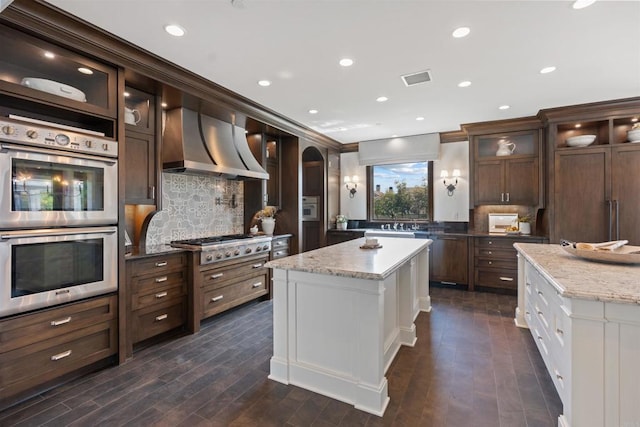 2574 Muirfields Dr, Carlsbad, CA 92009 - kitchen with appliances with stainless steel finishes, wall chimney range hood, backsplash, dark wood-style floors, and recessed lighting