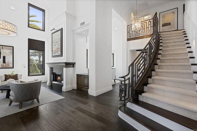 2574 Muirfields Dr, Carlsbad, CA 92009 - entryway with a chandelier, a towering ceiling, a lit fireplace, dark wood-type flooring, and stairway