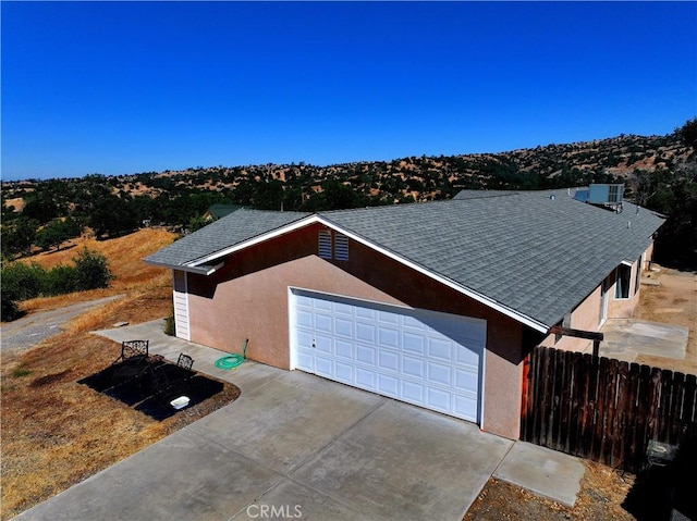 39560 S Lilley Way, Coarsegold, CA 93614 - view of property exterior with a shingled roof, a garage, stucco siding, and cooling unit