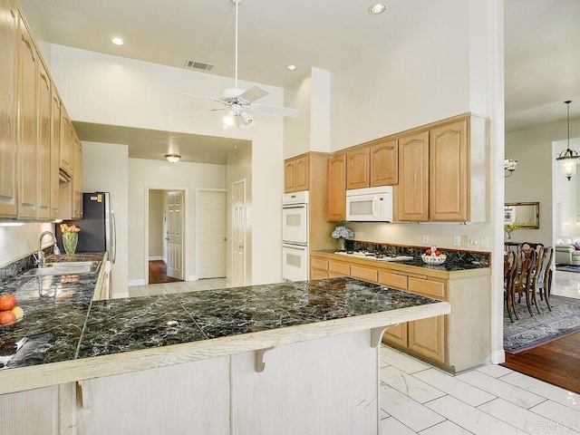 10237 High Mountain Dr, Escondido, CA 92026 - kitchen with white appliances, ceiling fan, a kitchen bar, a peninsula, and light marble finish flooring