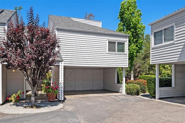 31531 Via Conejo Unit 153, Coto De Caza, CA 92679 - view of side of home featuring a garage, asphalt driveway, and a shingled roof