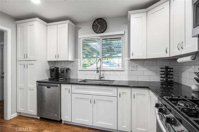 8506 Conway Dr, Riverside, CA 92504 - kitchen featuring dishwasher, a sink, white cabinets, decorative backsplash, and wood finished floors