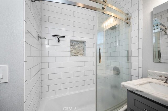 8506 Conway Dr, Riverside, CA 92504 - bathroom featuring combined bath / shower with glass door, vanity, and a textured wall