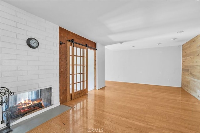 6325 Ridgepath Ct, Rancho Palos Verdes, CA 90275 - unfurnished living room featuring wood finished floors, a barn door, wooden walls, and a brick fireplace