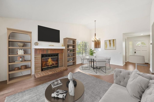 13398 Tiverton Rd, San Diego, CA 92130 - living area featuring wood finished floors, a chandelier, a brick fireplace, vaulted ceiling, and baseboards