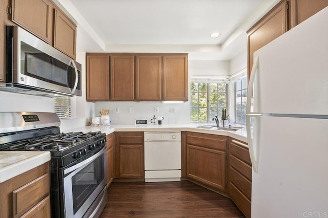 13398 Tiverton Rd, San Diego, CA 92130 - kitchen with stainless steel appliances, a sink, dark wood finished floors, brown cabinets, and recessed lighting