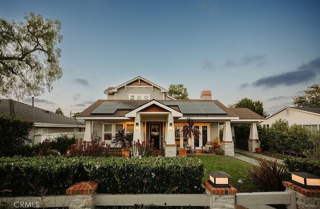 178 Flower St, Costa Mesa, CA 92627 - craftsman-style home with roof mounted solar panels, a chimney, stone siding, and a porch