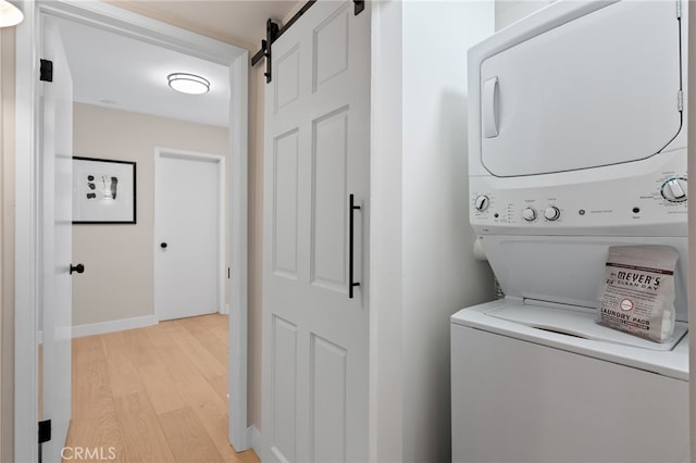 10707 Camarillo St Unit 314, North Hollywood, CA 91602 - washroom with stacked washing machine and dryer, light wood-style floors, a barn door, and baseboards