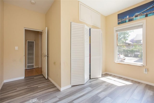 2712 Kenwood Ave, Los Angeles, CA 90007 - unfurnished bedroom featuring wood finished floors, a heating unit, a closet, and baseboards