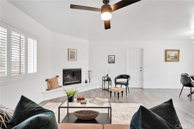 22331 Ramona Ave, Apple Valley, CA 92307 - living area with a ceiling fan, wood finished floors, a glass covered fireplace, and baseboards