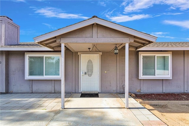 22331 Ramona Ave, Apple Valley, CA 92307 - view of exterior entry featuring a patio, roof with shingles, board and batten siding, and a chimney