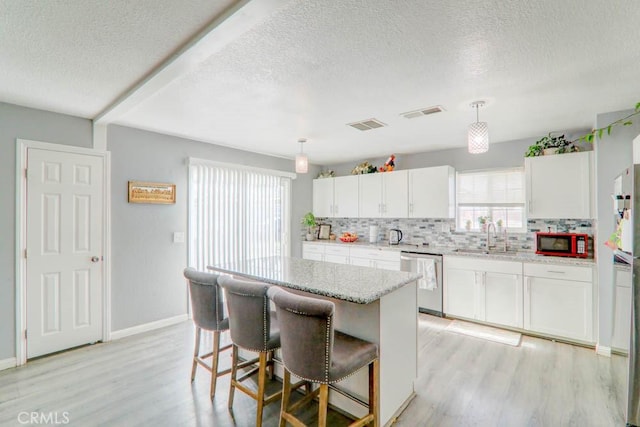 17152 Schollview Ave, Palmdale, CA 93591 - kitchen featuring stainless steel dishwasher, a textured ceiling, a sink, tasteful backsplash, and light wood-style flooring