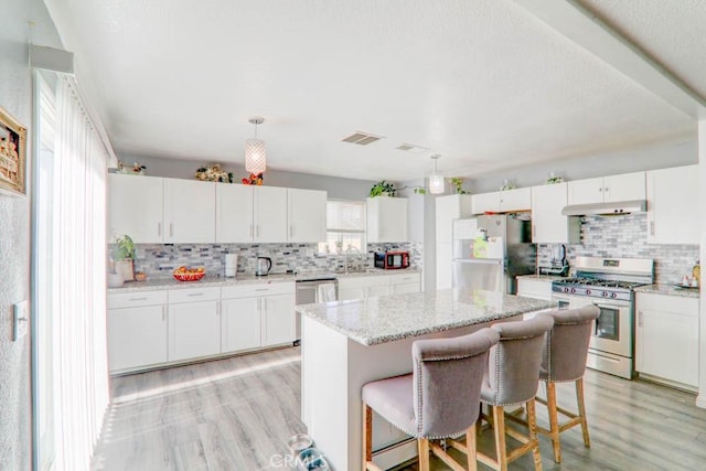 17152 Schollview Ave, Palmdale, CA 93591 - kitchen featuring appliances with stainless steel finishes, under cabinet range hood, decorative backsplash, light wood-style floors, and white cabinetry