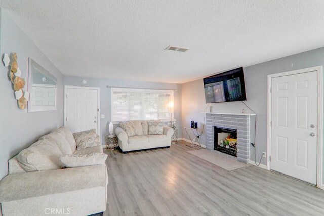 17152 Schollview Ave, Palmdale, CA 93591 - living area with a textured ceiling, light wood-style flooring, a fireplace, and baseboards