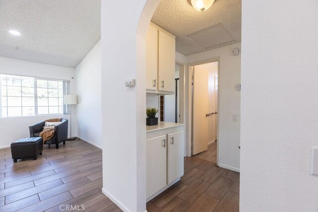 42117 Agena St, Temecula, CA 92592 - hall with wood finish floors, a textured ceiling, arched walkways, baseboards, and attic access