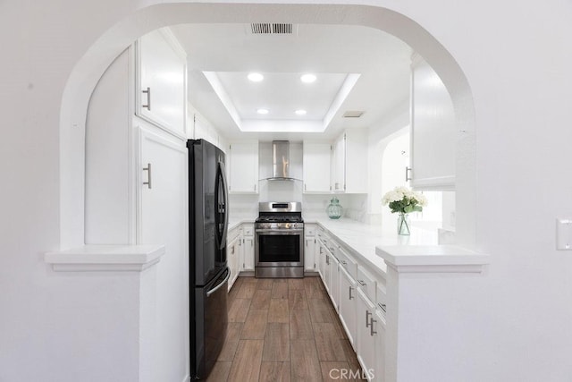 42117 Agena St, Temecula, CA 92592 - kitchen featuring gas stove, freestanding refrigerator, wall chimney range hood, a tray ceiling, and white cabinets